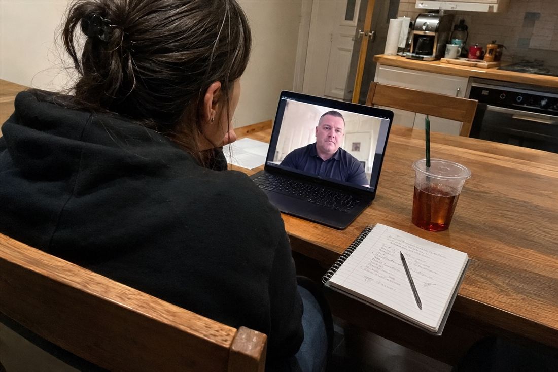 A woman at her kitchen table on a video call with a security professional