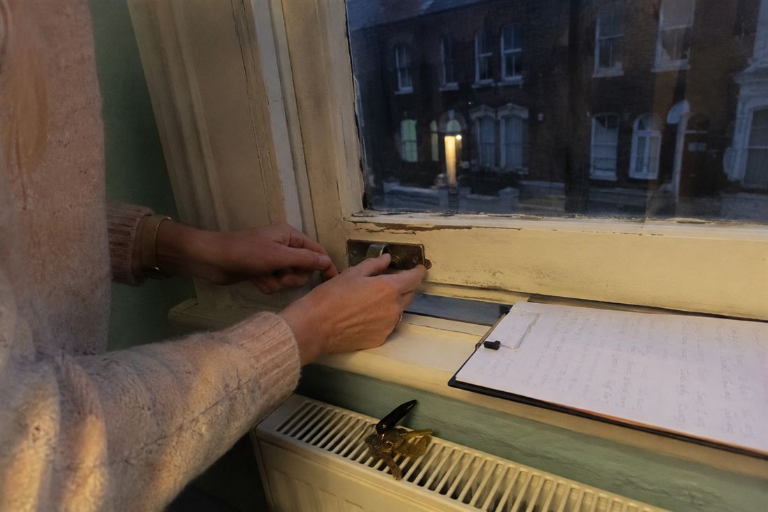 A woman's hands checking the lock on a sash window